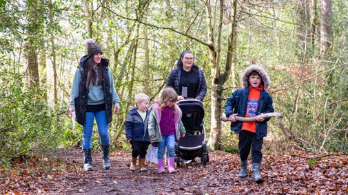 A group of adults and children on a winter walk through woodlands